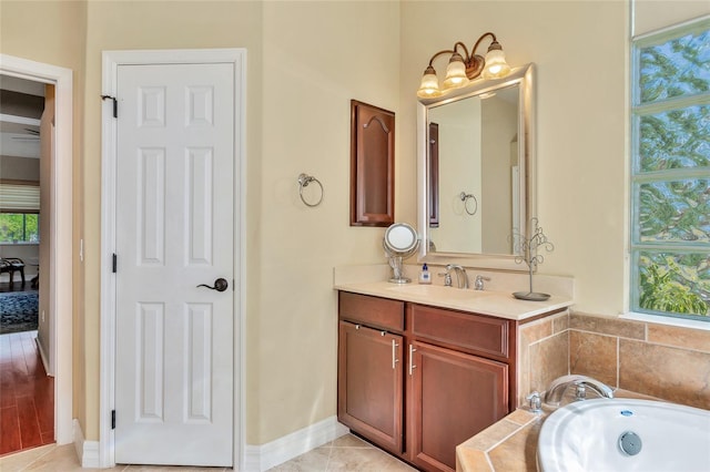 bathroom featuring a bathtub, vanity, a healthy amount of sunlight, and tile patterned flooring