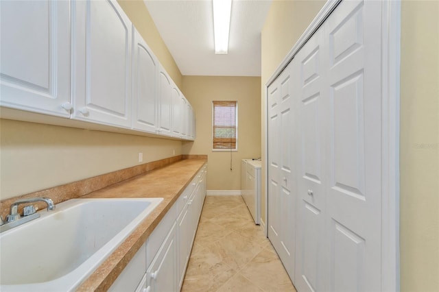 washroom featuring cabinets, sink, and washer and dryer