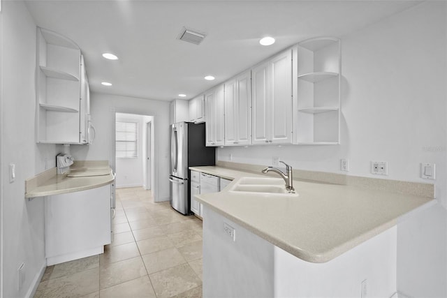 kitchen featuring white cabinets, sink, light tile patterned flooring, kitchen peninsula, and stainless steel refrigerator