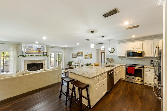 kitchen with a wealth of natural light, light stone countertops, decorative light fixtures, and appliances with stainless steel finishes