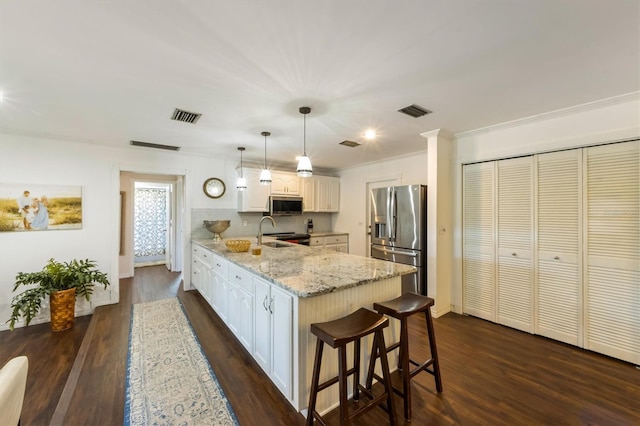 kitchen with appliances with stainless steel finishes, dark hardwood / wood-style flooring, white cabinetry, and pendant lighting