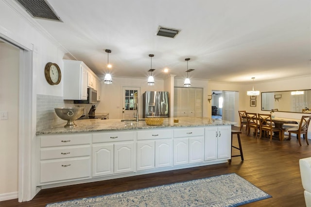 kitchen with dark wood-type flooring, tasteful backsplash, stainless steel fridge, decorative light fixtures, and white cabinets