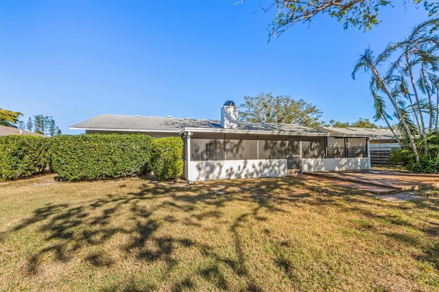 rear view of property with a lawn and a sunroom