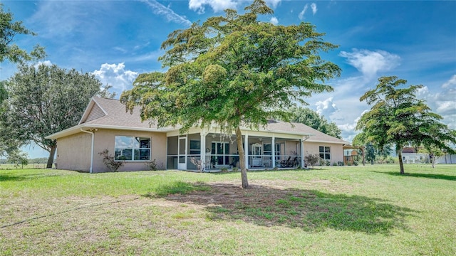 back of house featuring a lawn and a sunroom