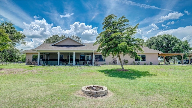 view of front of house with a sunroom, an outdoor fire pit, and a front lawn