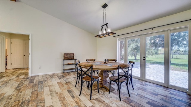 dining room with french doors, light hardwood / wood-style floors, and vaulted ceiling