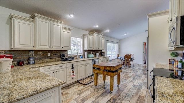 kitchen featuring lofted ceiling, sink, decorative backsplash, light hardwood / wood-style floors, and stainless steel appliances