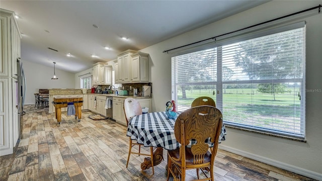 dining space with sink, light hardwood / wood-style floors, and lofted ceiling