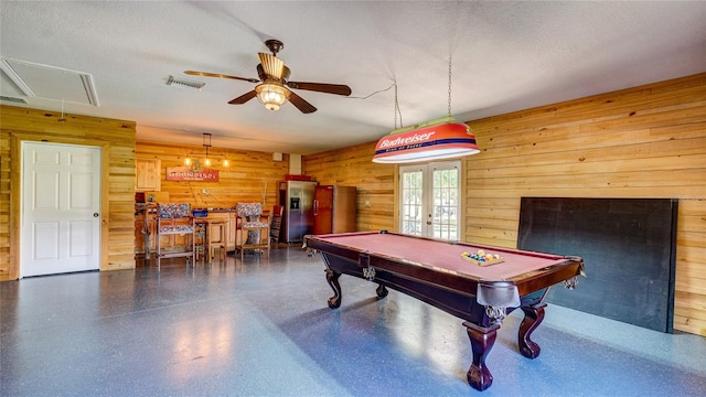 recreation room featuring wooden walls, french doors, and a textured ceiling