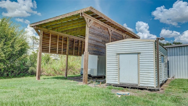 view of outdoor structure with a carport and a lawn