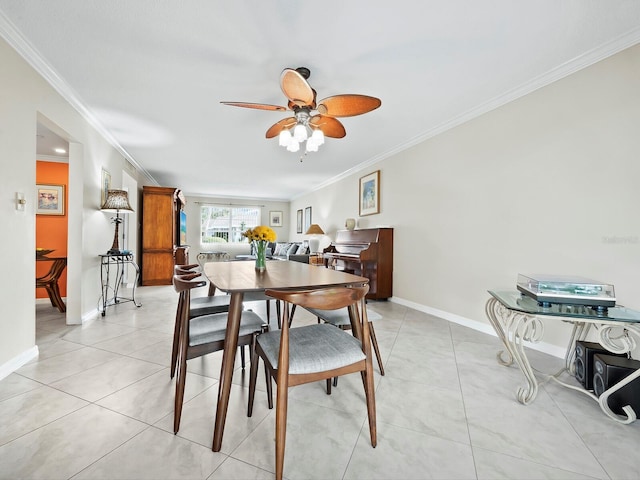 tiled dining space with ceiling fan and crown molding