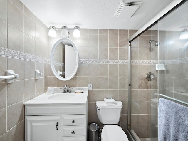 bathroom with walk in shower, vanity, toilet, and tile walls