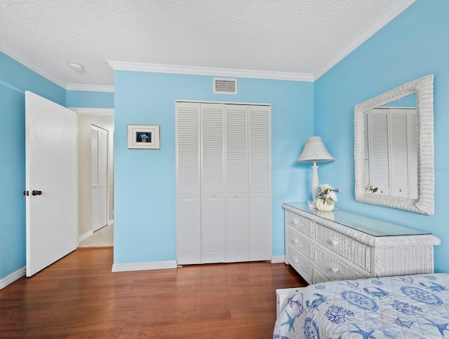 bedroom featuring dark hardwood / wood-style floors, ornamental molding, a textured ceiling, and two closets