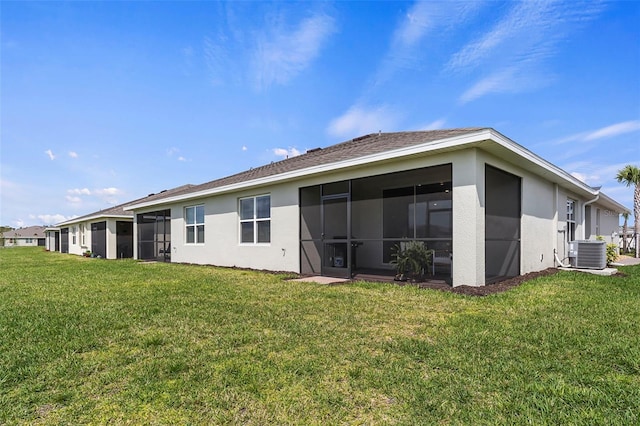 rear view of property featuring a lawn, a sunroom, and central AC