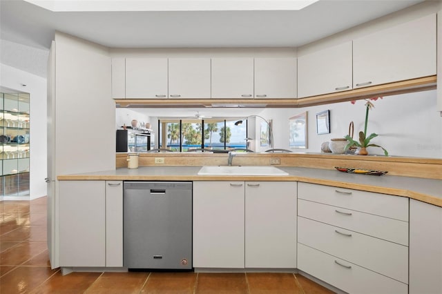 kitchen featuring dishwasher, light tile patterned floors, white cabinets, and sink