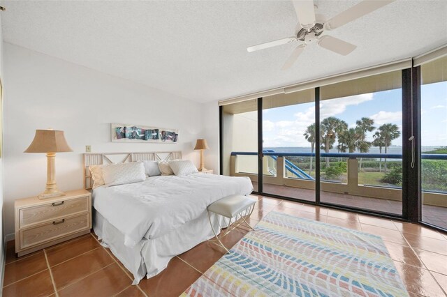 tiled bedroom with ceiling fan, expansive windows, access to exterior, and a textured ceiling