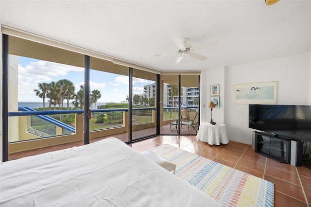 tiled bedroom with expansive windows, a textured ceiling, access to outside, and ceiling fan