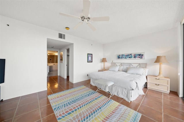 bedroom featuring a textured ceiling, dark tile patterned flooring, and ceiling fan