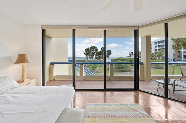 bedroom with ceiling fan, expansive windows, a textured ceiling, and access to outside