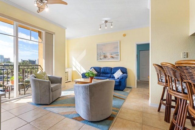 living room with light tile patterned floors, ceiling fan, and ornamental molding