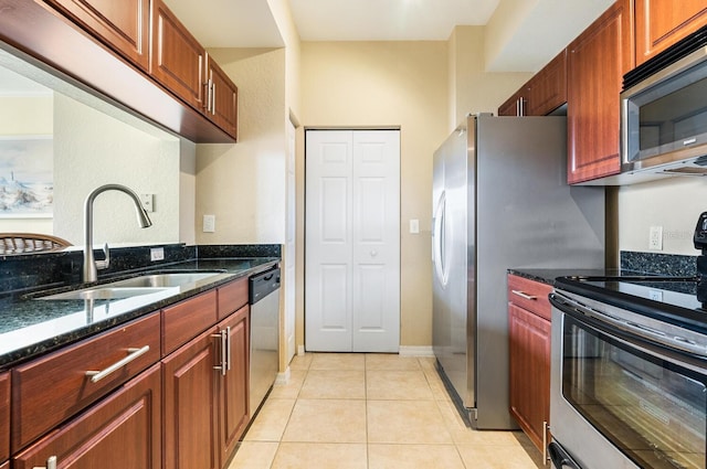 kitchen featuring light tile patterned flooring, appliances with stainless steel finishes, dark stone countertops, and sink