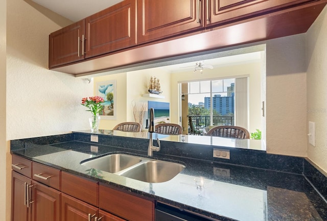 kitchen with ceiling fan, dark stone countertops, and sink