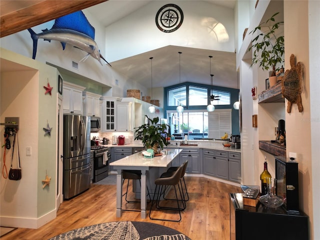 kitchen featuring white cabinets, stainless steel appliances, gray cabinets, and light hardwood / wood-style flooring