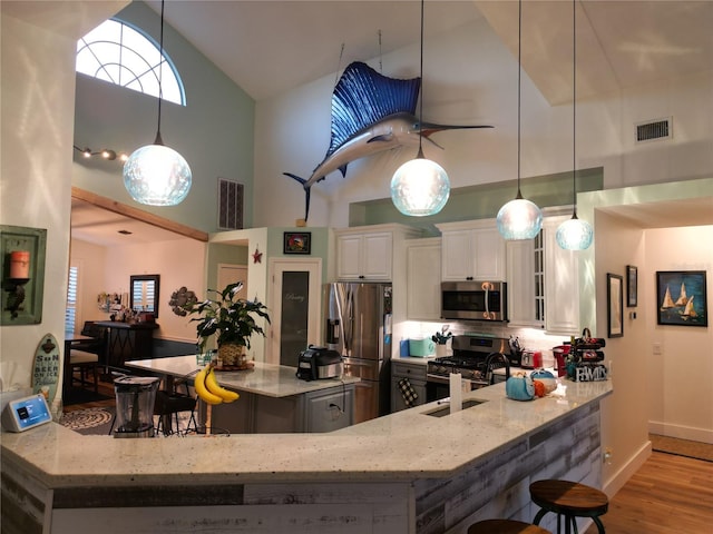 kitchen featuring light stone counters, stainless steel appliances, sink, high vaulted ceiling, and white cabinets