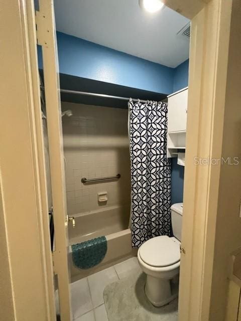 bathroom featuring tile patterned floors, toilet, and shower / bath combo with shower curtain