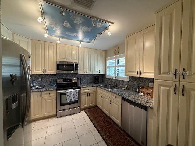 kitchen featuring backsplash, appliances with stainless steel finishes, sink, and dark stone counters