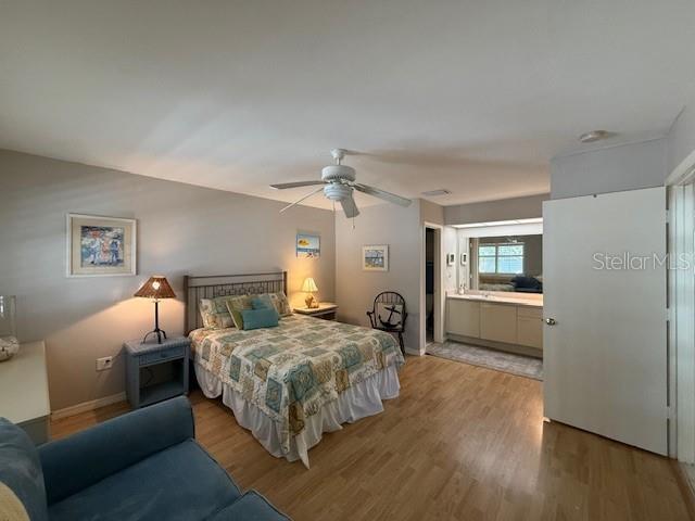 bedroom featuring hardwood / wood-style flooring, ceiling fan, and ensuite bath