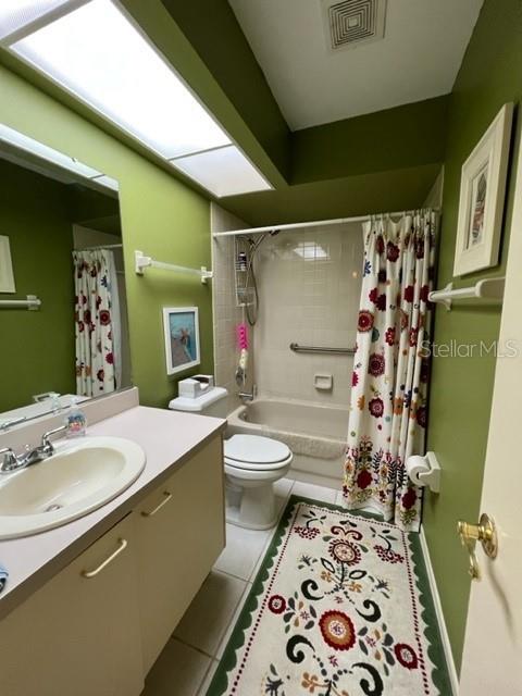 full bathroom featuring toilet, vanity, shower / bathtub combination with curtain, and tile patterned flooring