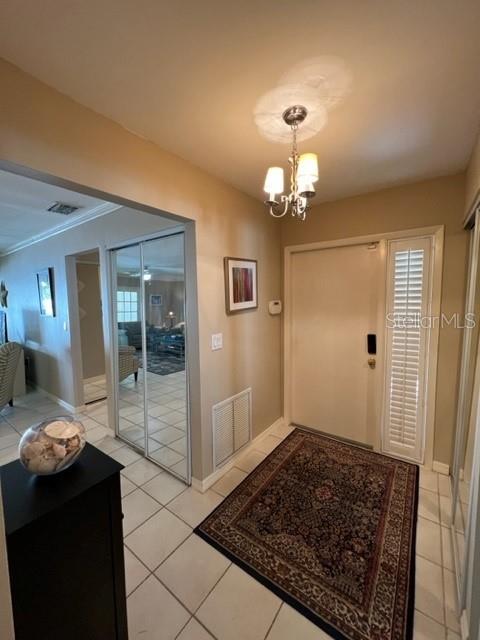 entryway with light tile patterned flooring and a chandelier