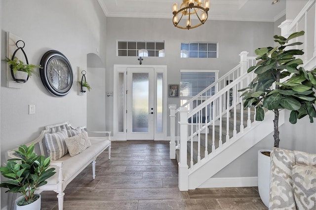 foyer entrance with a notable chandelier, ornamental molding, dark wood-type flooring, and a towering ceiling