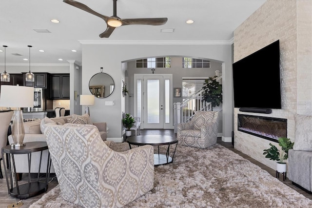 living room featuring a fireplace, hardwood / wood-style flooring, ceiling fan, and crown molding