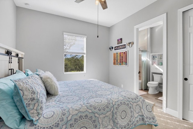 bedroom featuring light wood-type flooring, connected bathroom, and ceiling fan