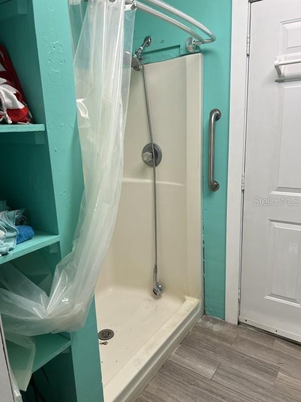 bathroom with a shower with shower curtain and hardwood / wood-style floors