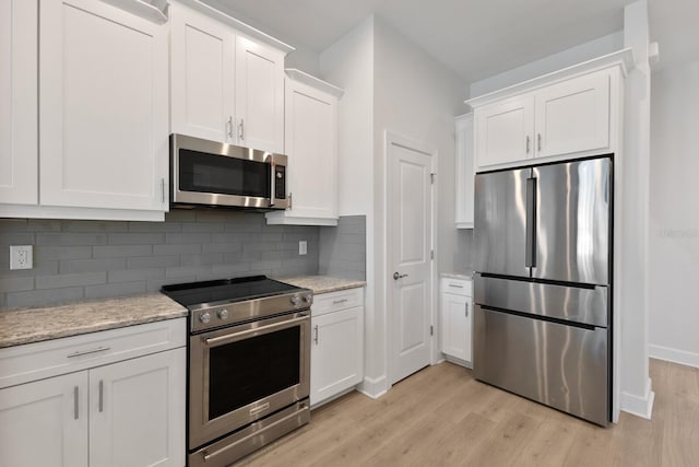 kitchen with appliances with stainless steel finishes, light wood-type flooring, and white cabinetry