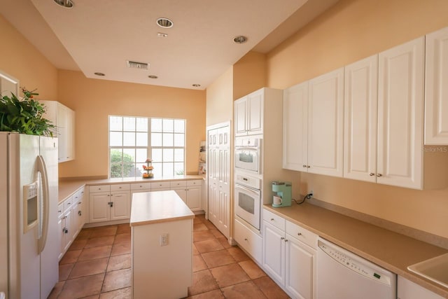 kitchen featuring white cabinets, light tile patterned floors, white appliances, and a center island