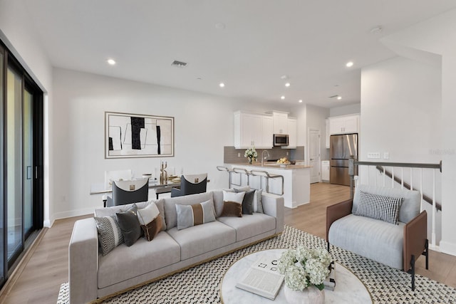 living room featuring sink and light hardwood / wood-style floors