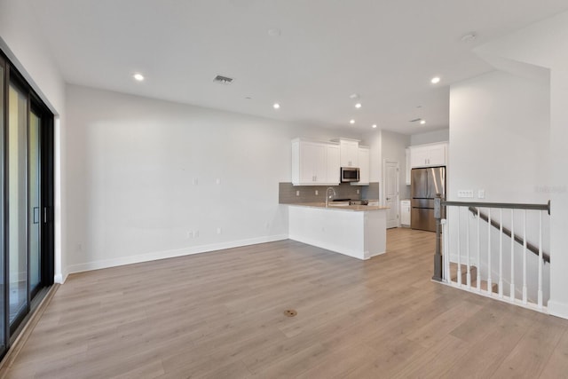 unfurnished living room featuring light wood-type flooring and sink