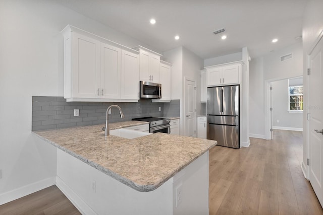 kitchen featuring kitchen peninsula, light wood-type flooring, stainless steel appliances, sink, and white cabinetry