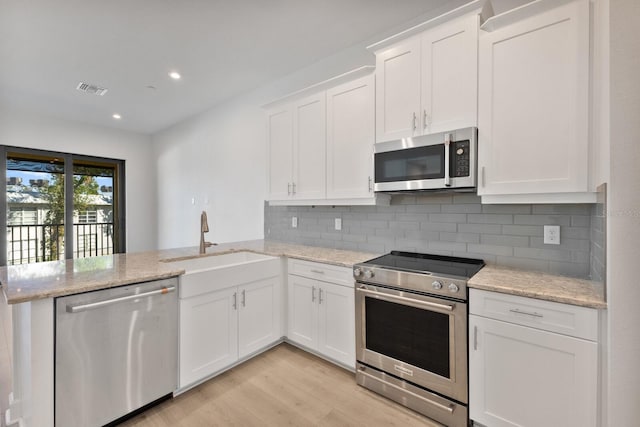 kitchen featuring kitchen peninsula, white cabinetry, sink, and appliances with stainless steel finishes