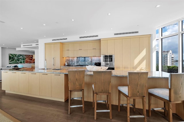 kitchen with dark hardwood / wood-style floors, a healthy amount of sunlight, light stone counters, and light brown cabinets