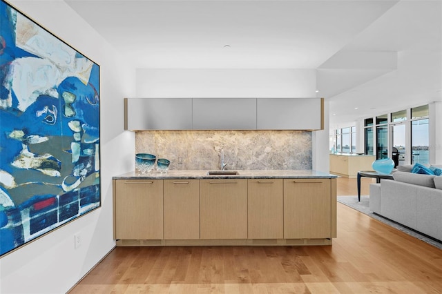 kitchen featuring backsplash, light brown cabinets, light hardwood / wood-style floors, and sink