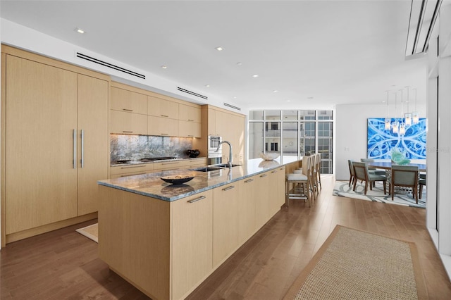 kitchen featuring light brown cabinets, a large island with sink, and light hardwood / wood-style flooring