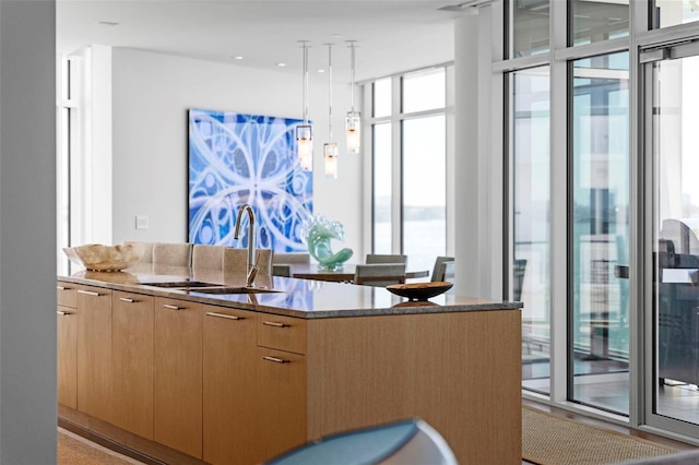 kitchen featuring light brown cabinetry, a center island, pendant lighting, and sink