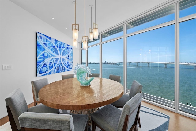 dining space featuring expansive windows, a water view, hardwood / wood-style flooring, and a notable chandelier