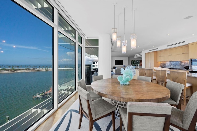 dining space with a wealth of natural light, a water view, and wood-type flooring