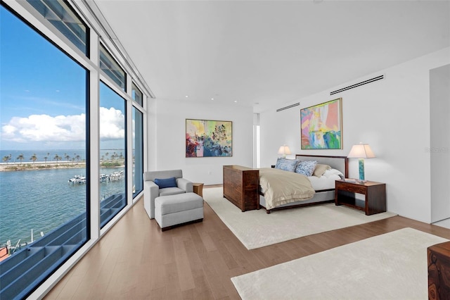 bedroom with a water view, wood-type flooring, and access to outside